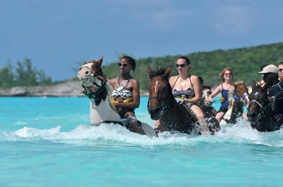 Jóvenes del Cuba Clan montando a caballo en una playa virgen de Cuba al atardecer