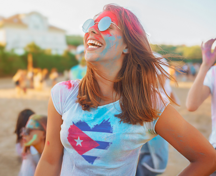 Joven sonriente en una playa de Cuba con camiseta cubana, disfrutando del viaje en grupo